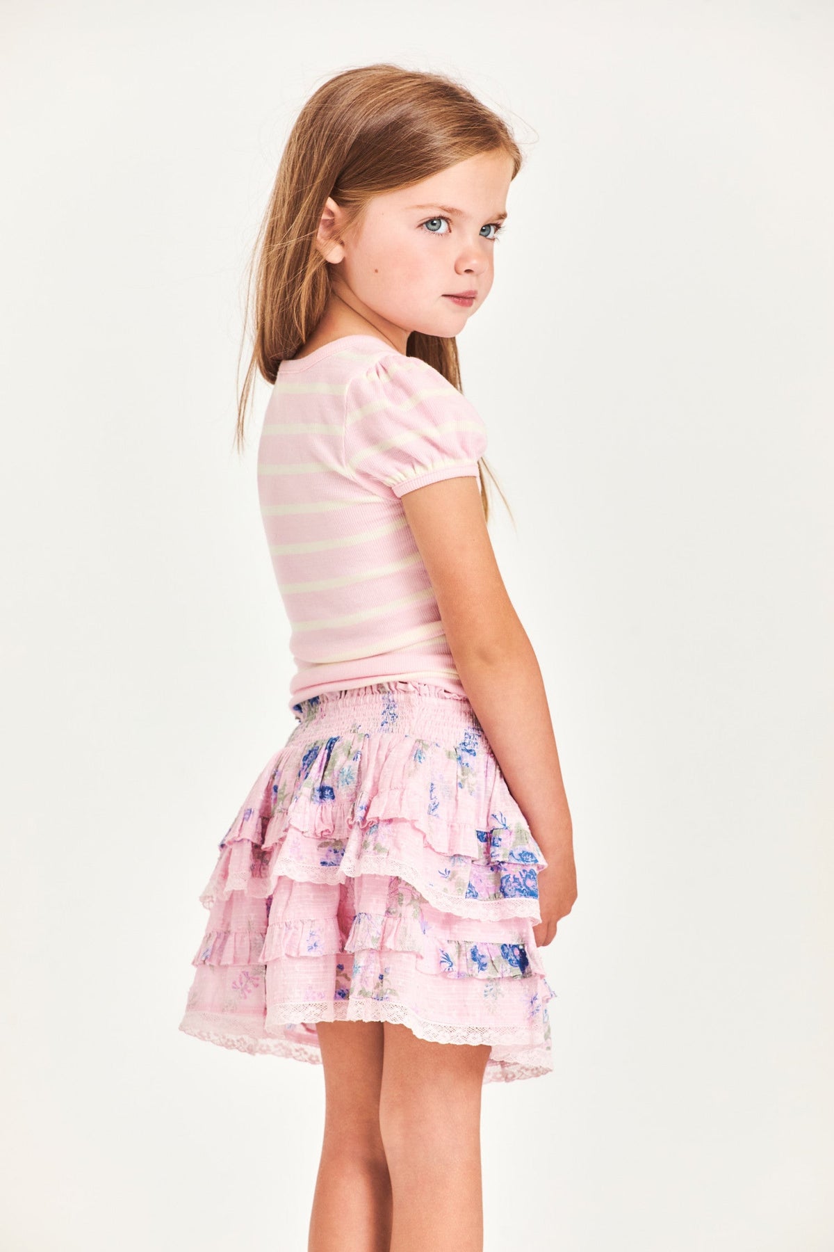 The Billie Skirt is 100% cotton and features a wide smocked waistband with two shirred tiers and ruffle detailing. It is a beautiful baby pink with blue flower detailing.