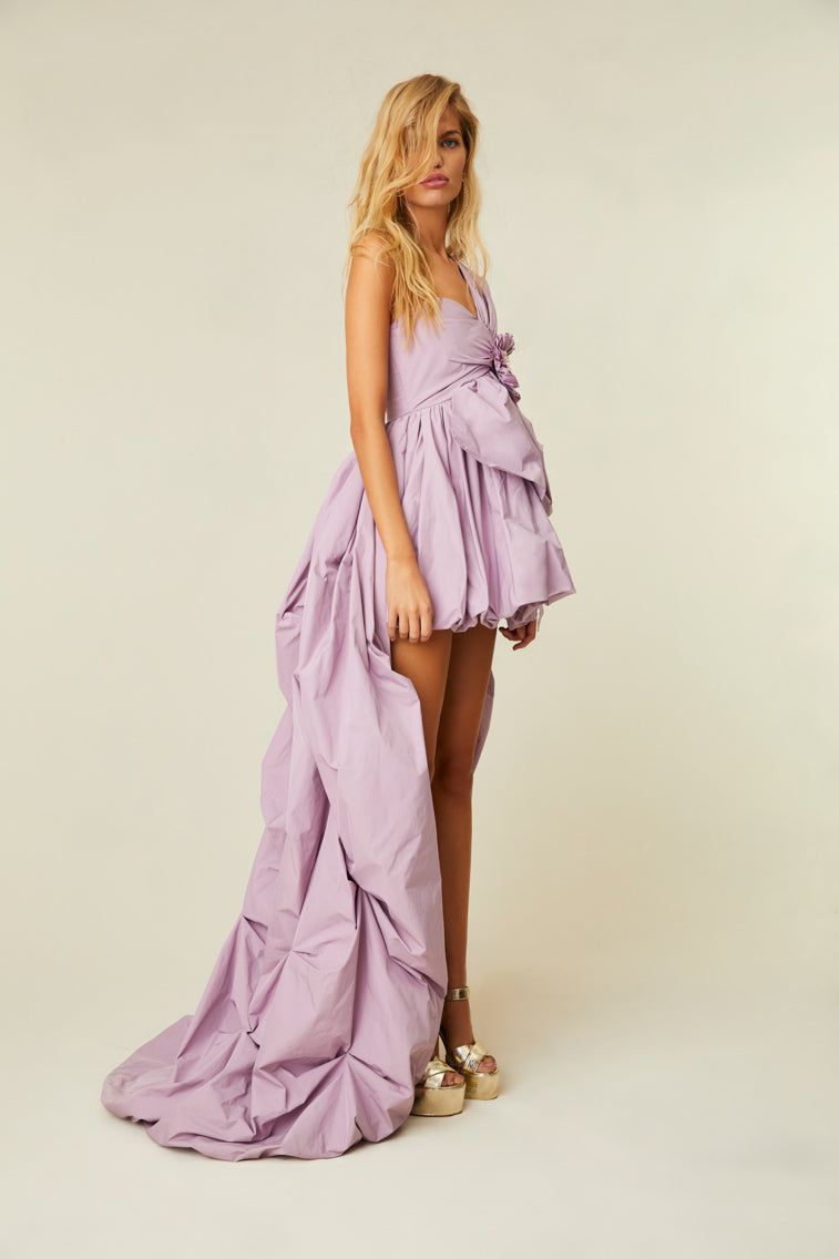 Lavender gown with a one shoulder, high-to-low silhouette that features a ruched bodice, a rosette detailing, and crystals.