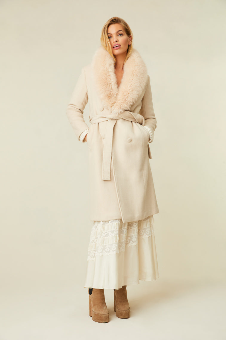 The cream-colored jacket features a faux fur collar, pockets, and a belt.