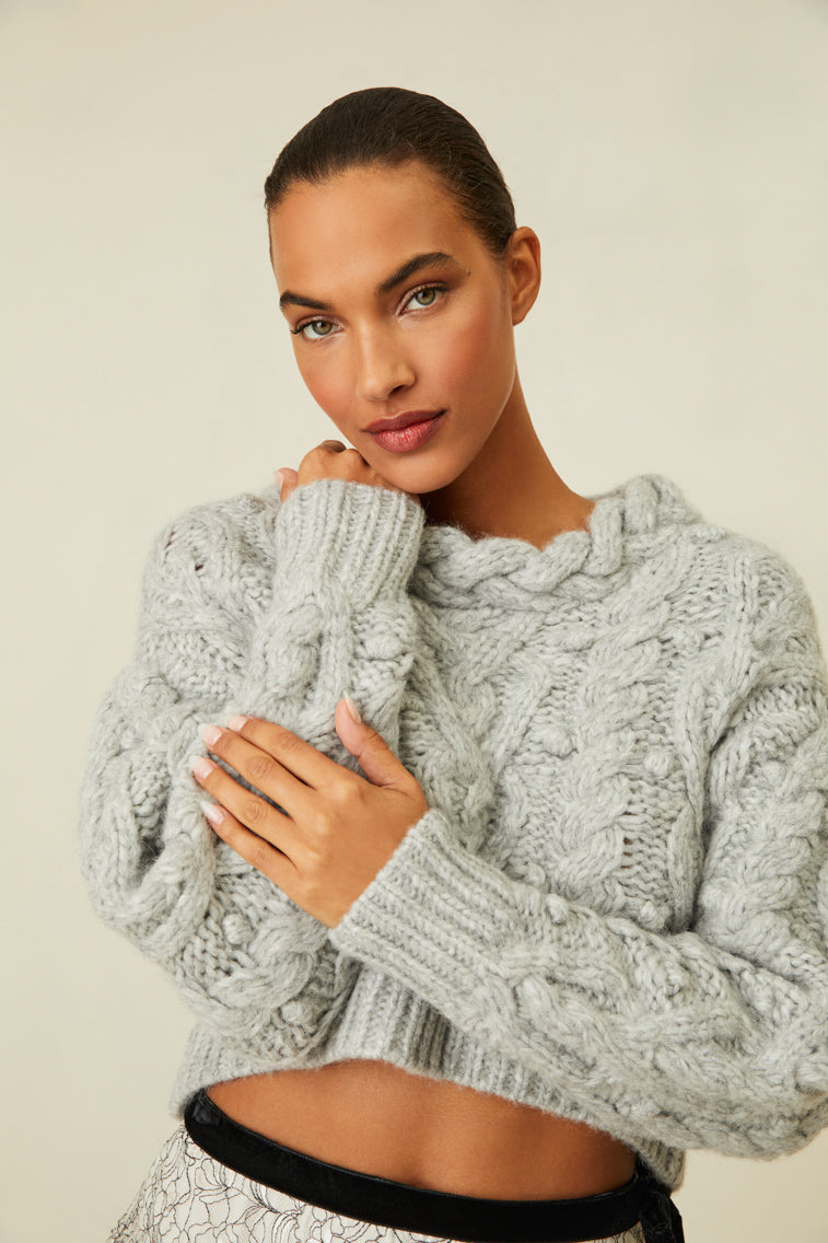 Cable knit sweater with chunky braided neckline and a high-to-low silhouette.