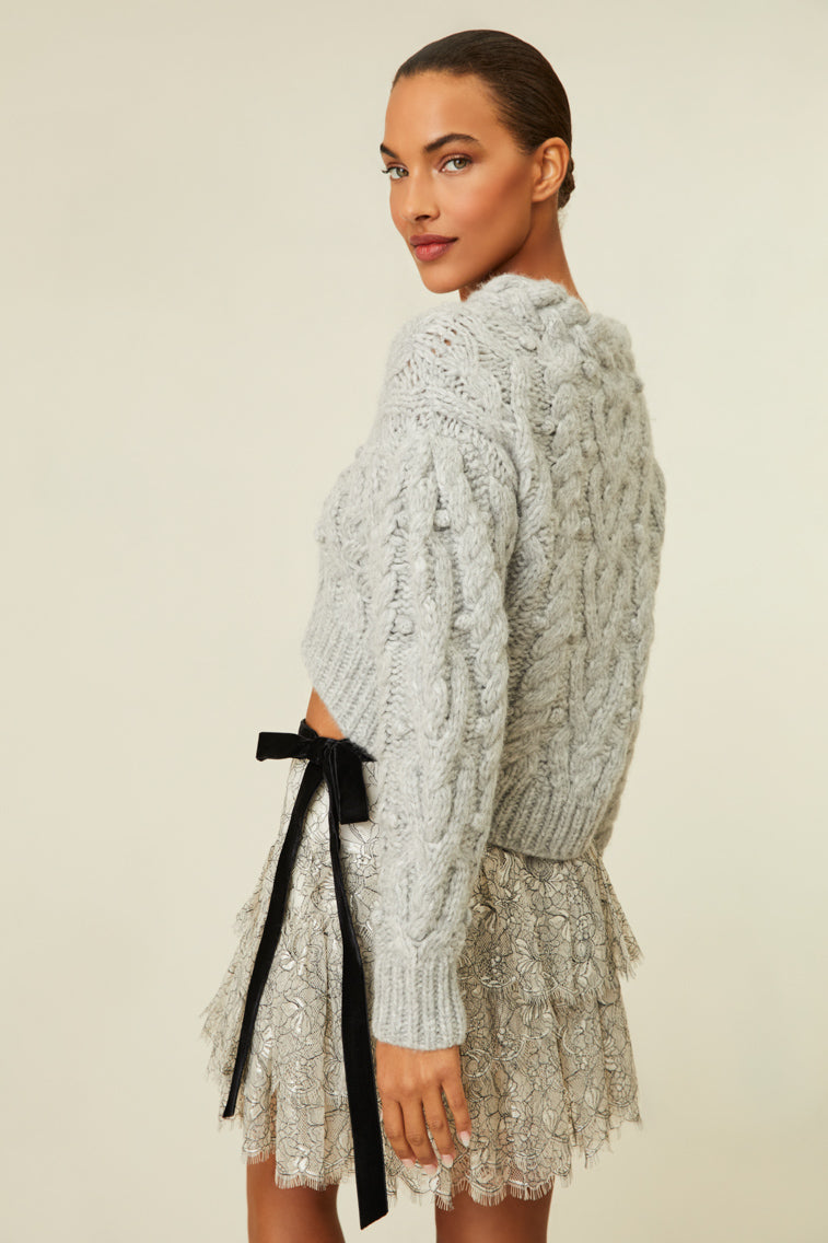 Cable knit sweater with chunky braided neckline and a high-to-low silhouette.