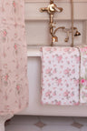 vintage-inspired repeating floral print bath towel in a soft pink against a white back