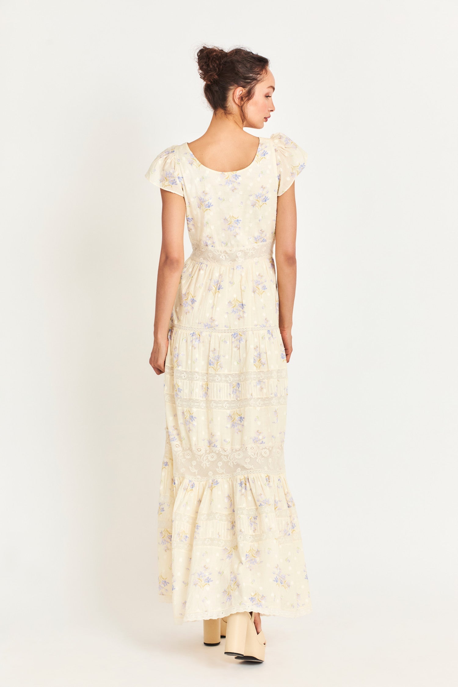 The Melinda Dress is a Victorian-inspired maxi dress in a baby yellow features a textured clip-dotted heart shape lobby fabric cotton and is adorned with a medley of beautiful custom laces. It has sweet flutter sleeves and a flirty open neck. 