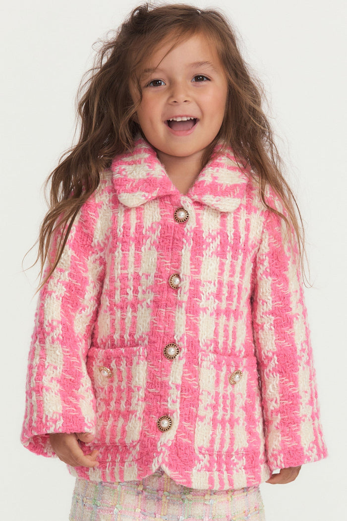 Little girl with pink and white houndstooth print wool jacket with pearl buttons, and pockets.