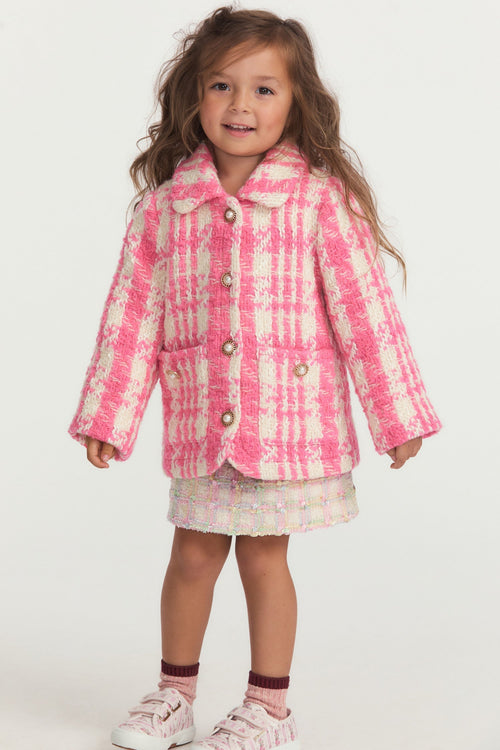 Little girl with pink and white houndstooth print wool jacket with pearl buttons, and pockets.