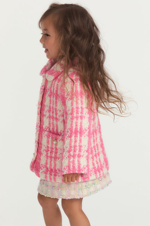 Little girl with pink and white houndstooth print wool jacket with pearl buttons, and pockets.