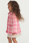 Little girl with pink and white houndstooth print wool jacket with pearl buttons, and pockets.
