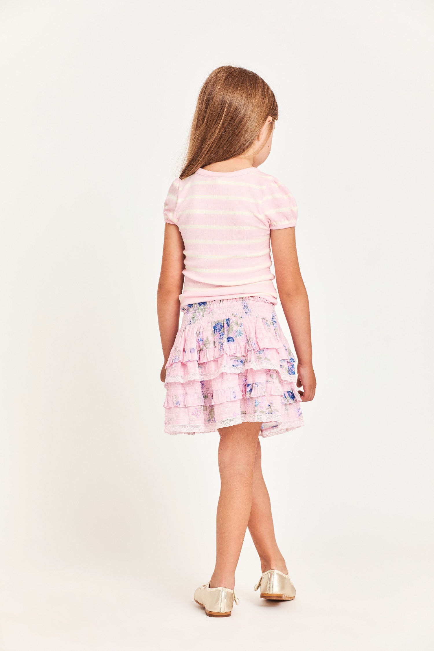 The Billie Skirt is 100% cotton and features a wide smocked waistband with two shirred tiers and ruffle detailing. It is a beautiful baby pink with blue flower detailing.  