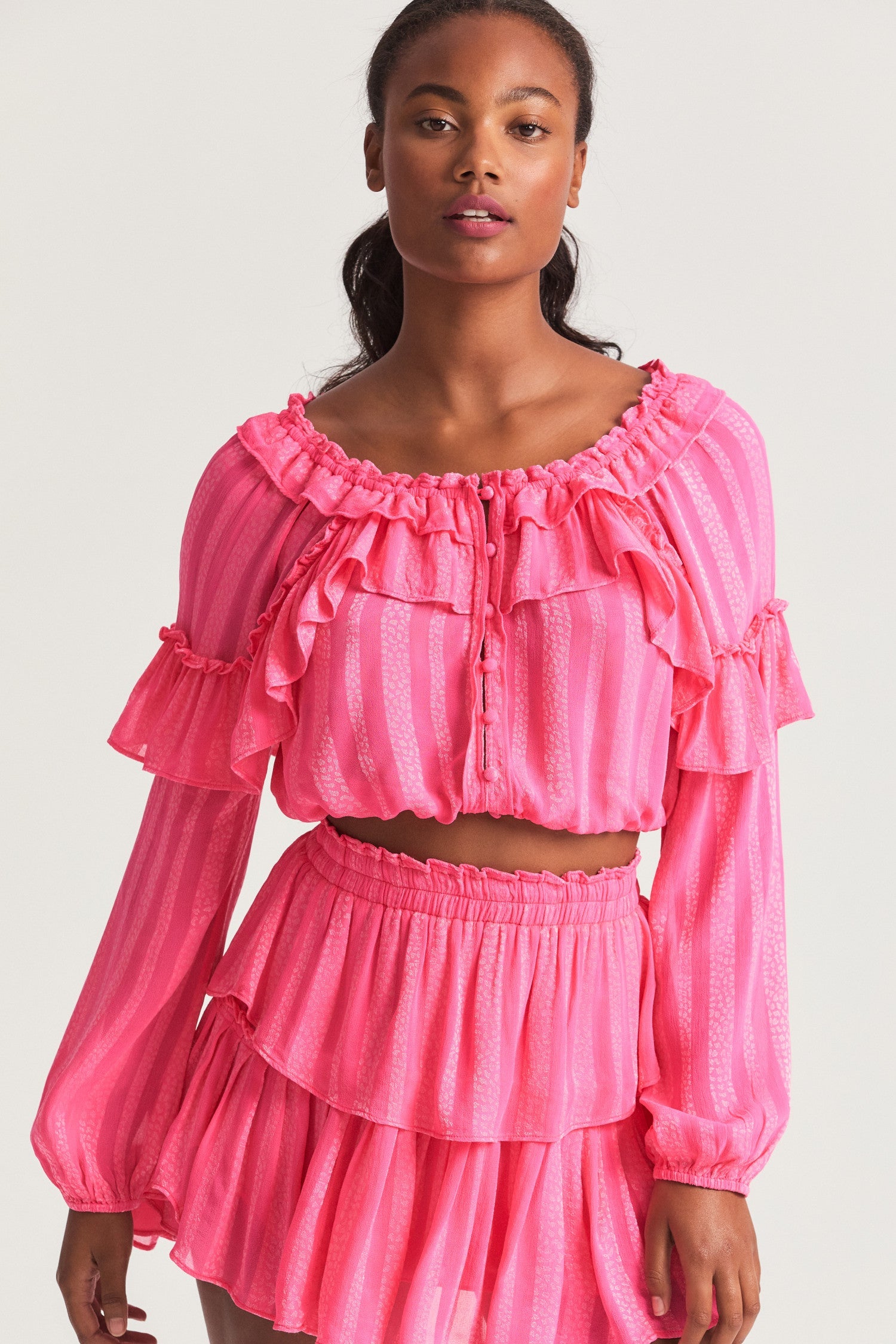 Pink long sleeved-top features a striped jacquard fabric, dramatic ruffles all over, an elasticated waist, elastic at the sleeve openings, and a fully functioning center front slit.