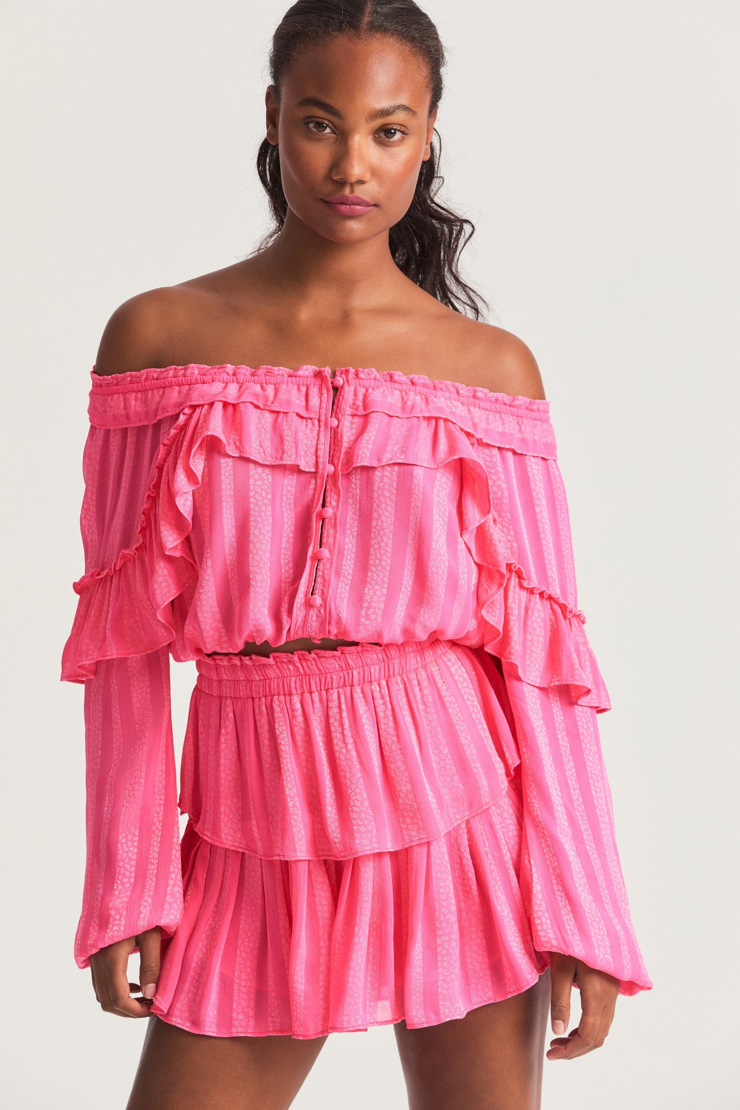 Pink long sleeved-top features a striped jacquard fabric, dramatic ruffles all over, an elasticated waist, elastic at the sleeve openings, and a fully functioning center front slit.