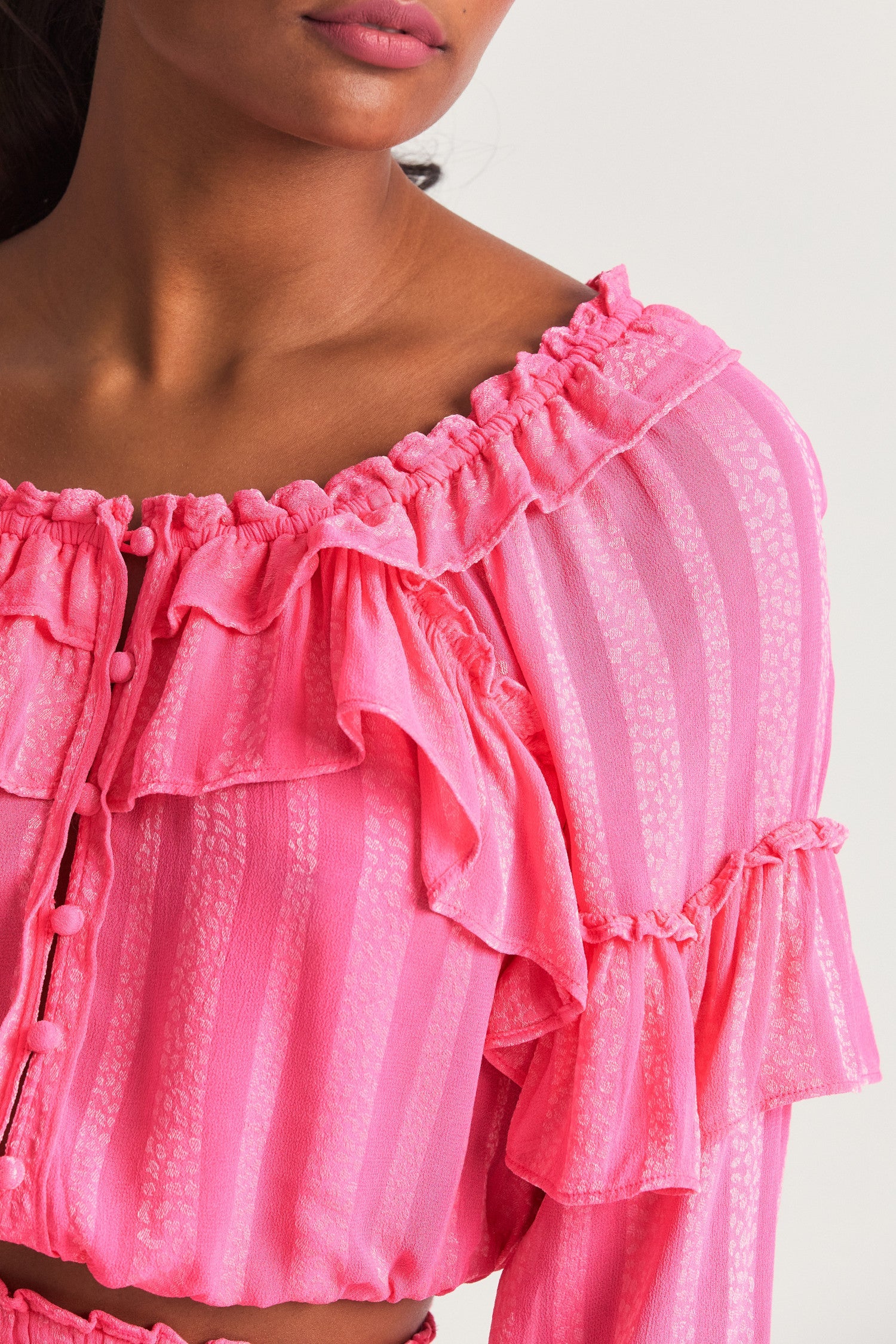 Pink long sleeved-top features a striped jacquard fabric, dramatic ruffles all over, an elasticated waist, elastic at the sleeve openings, and a fully functioning center front slit.