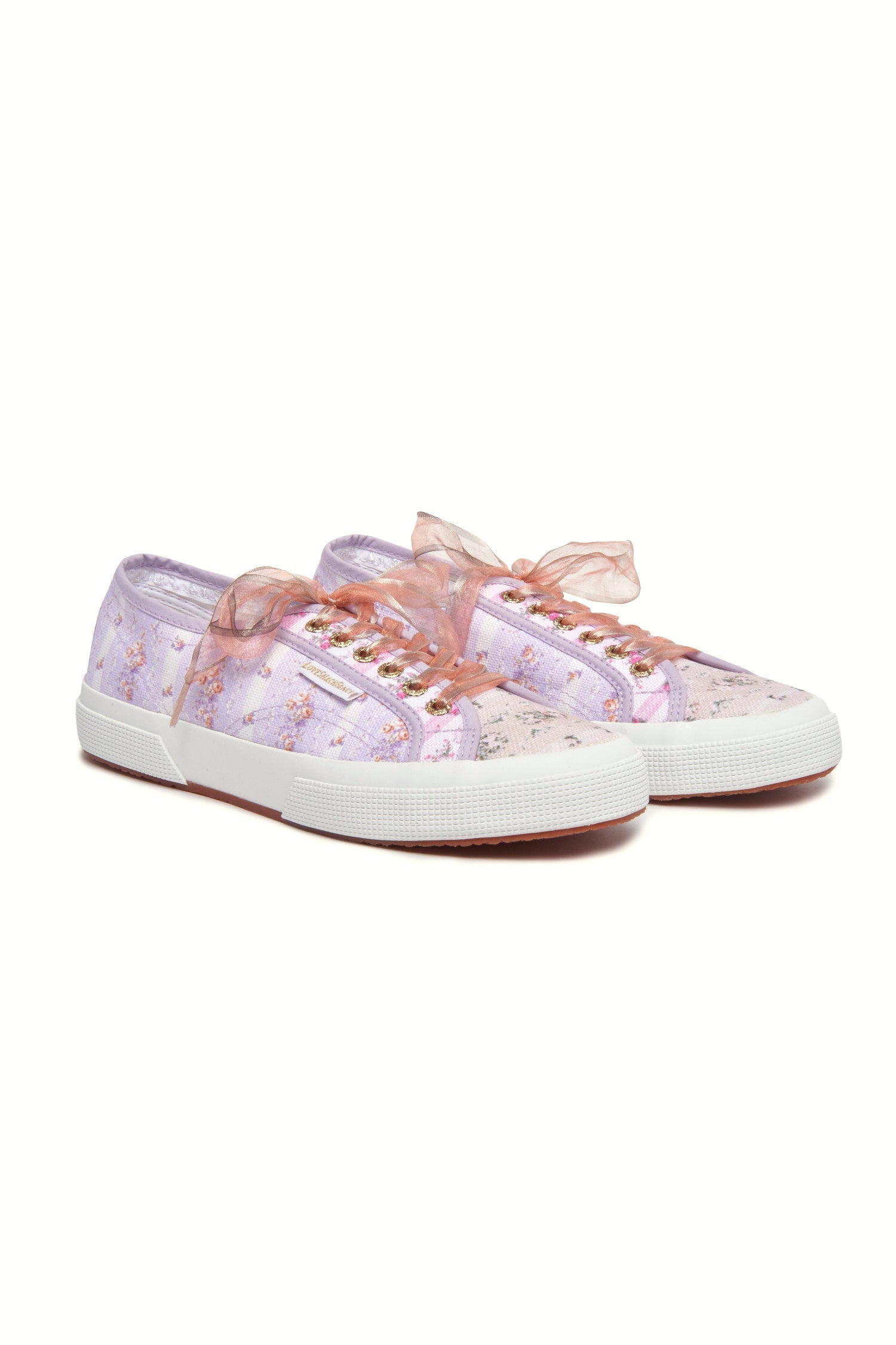 Pastel lilac sneaker with floral pattern on printed cotton, gold-toned eyelet details, and pink organza laces.