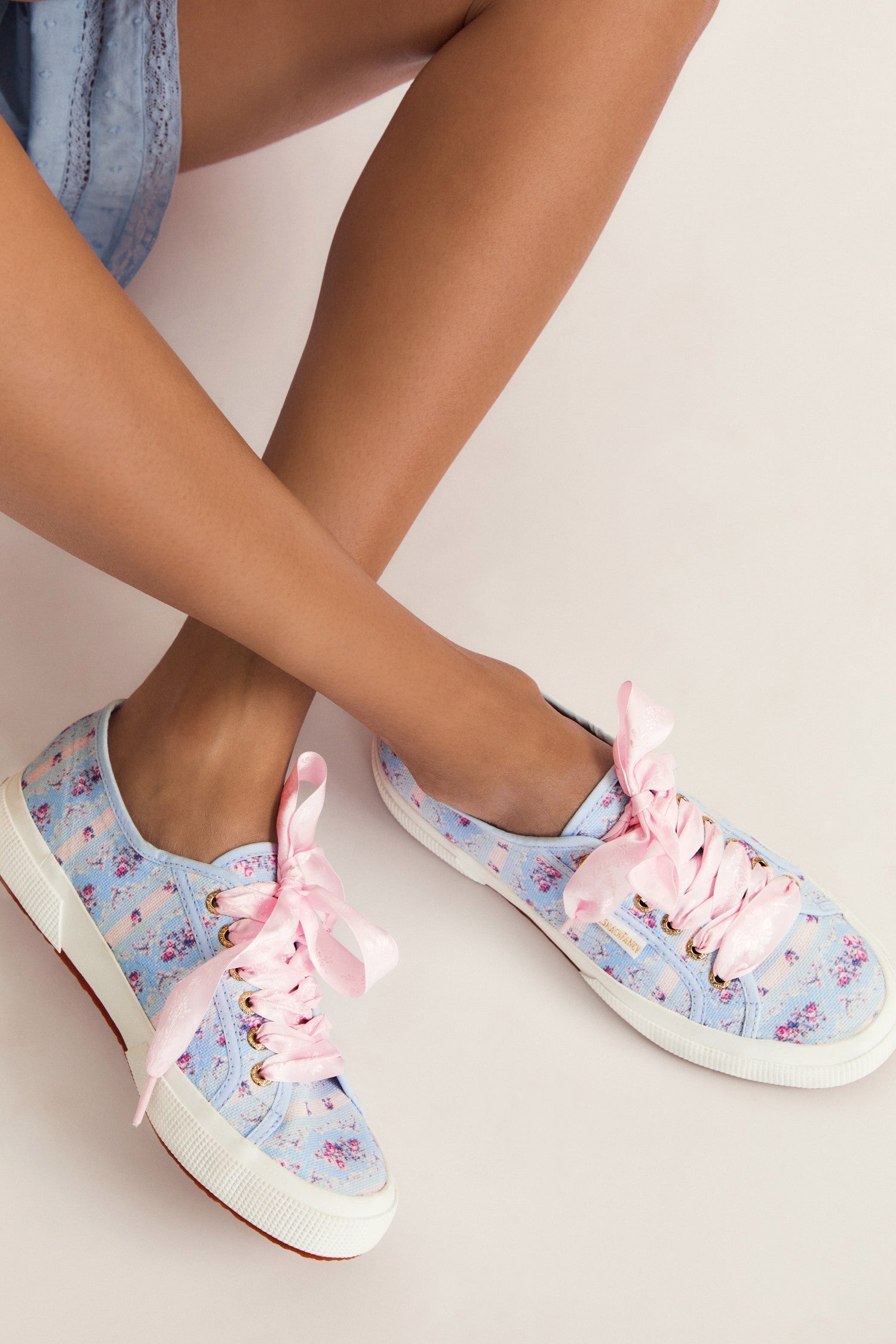 Pastel blue sneaker with floral pattern on printed cotton, gold-toned eyelet details, and pink velvet laces.