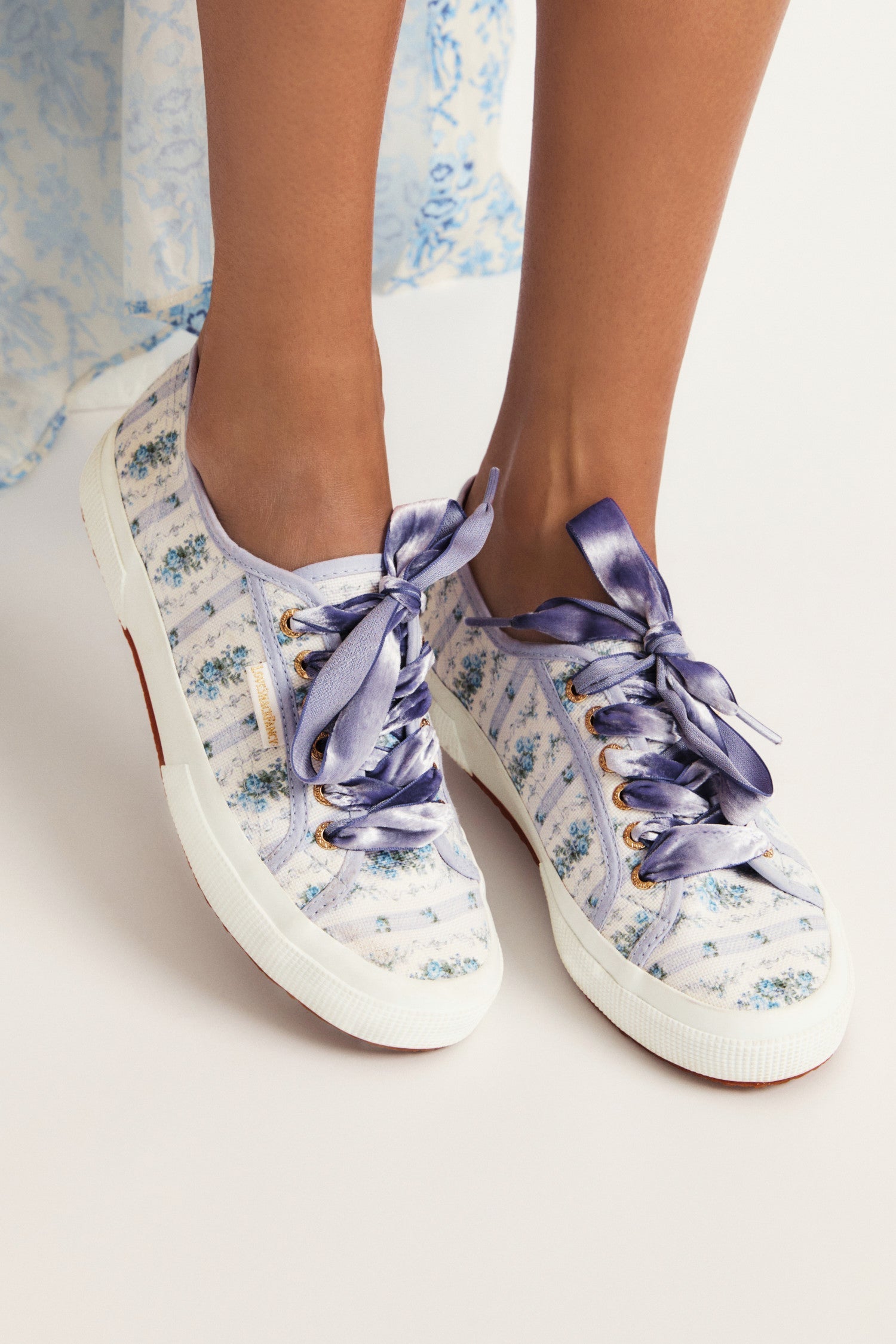 Pastel purple/lilac sneaker with floral pattern on printed cotton, gold-toned eyelet details, and purple velvet laces.