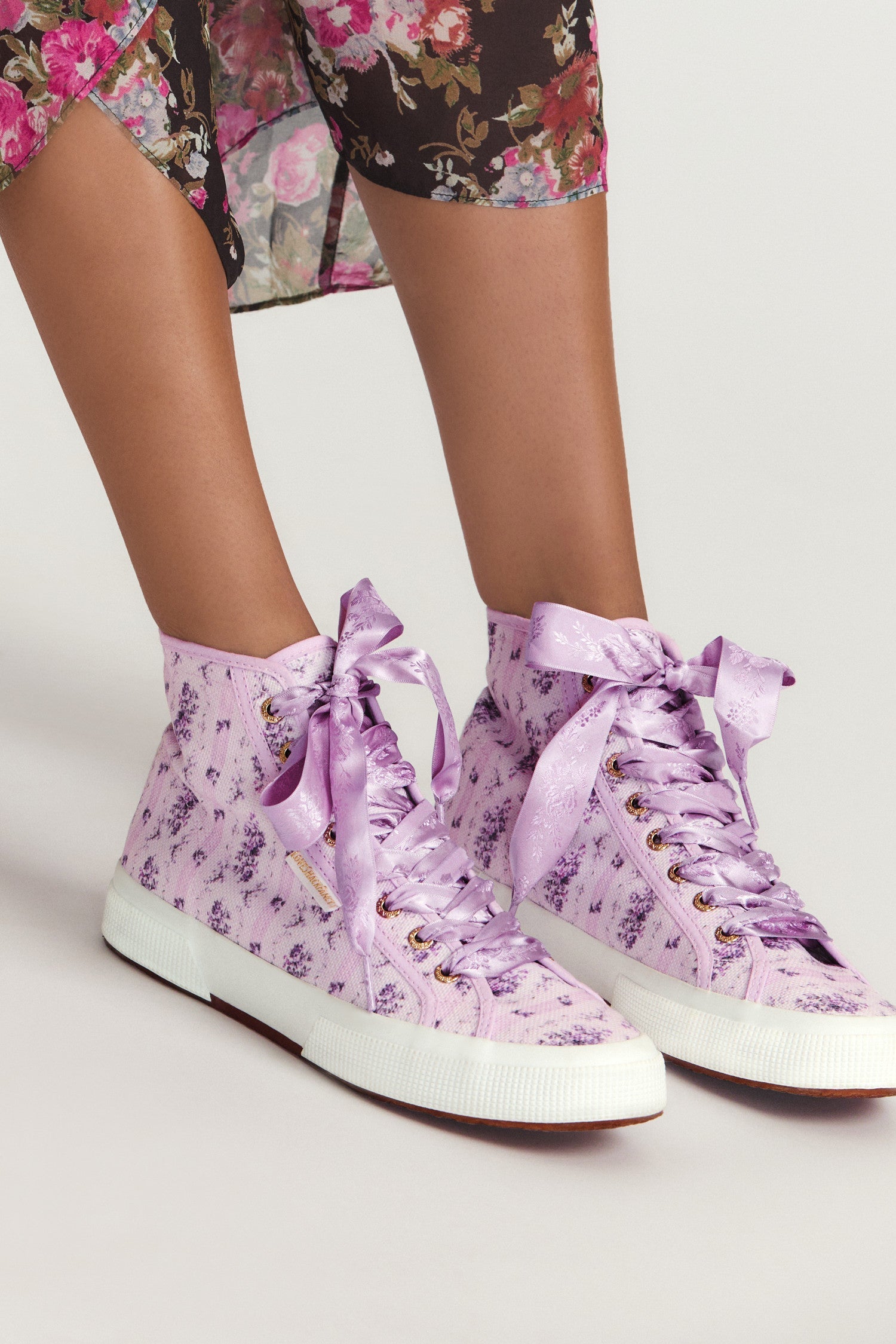 Purple hightop sneakers with florals on printed cotton with purple satin laces, and gold-tone eyelet details.