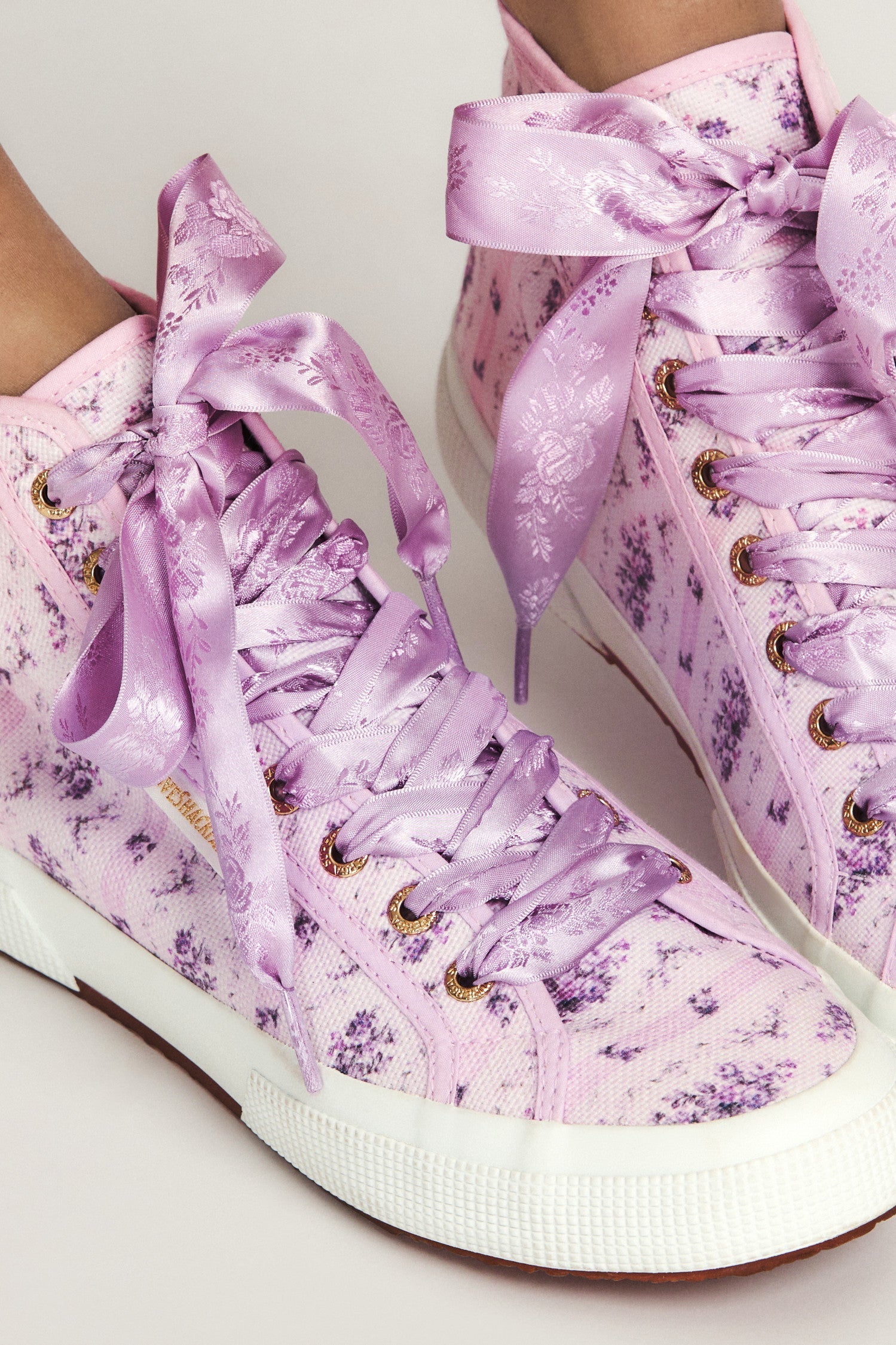 Purple hightop sneakers with florals on printed cotton with purple satin laces, and gold-tone eyelet details.