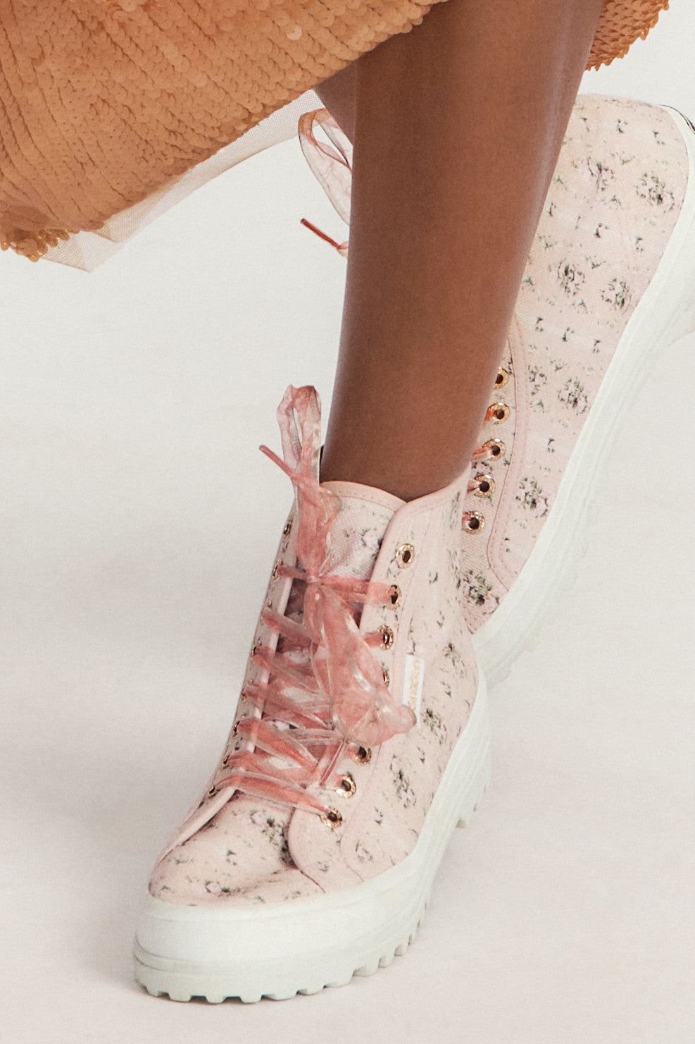 Pink hightop sneakers with florals on printed cotton with pink tulle laces, and gold-tone eyelet details.