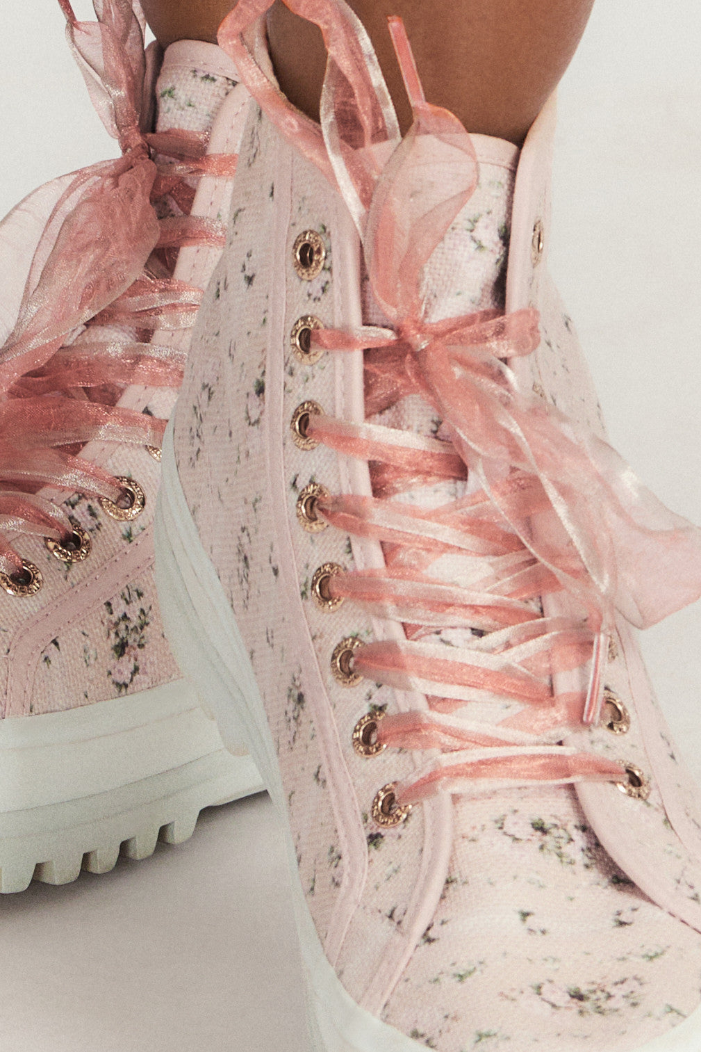 Pink hightop sneakers with florals on printed cotton with pink tulle laces, and gold-tone eyelet details.