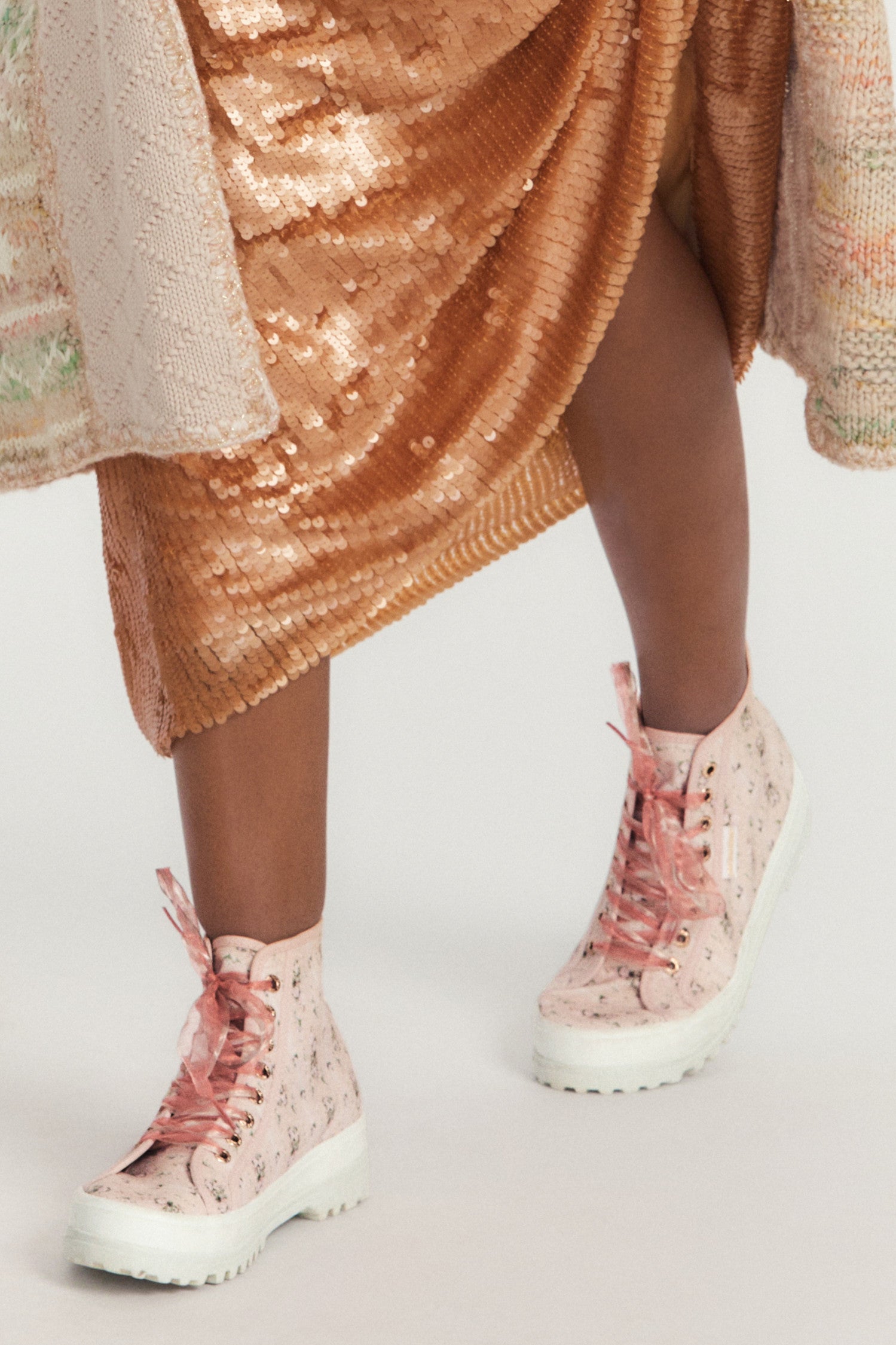 Pink hightop sneakers with florals on printed cotton with pink tulle laces, and gold-tone eyelet details.