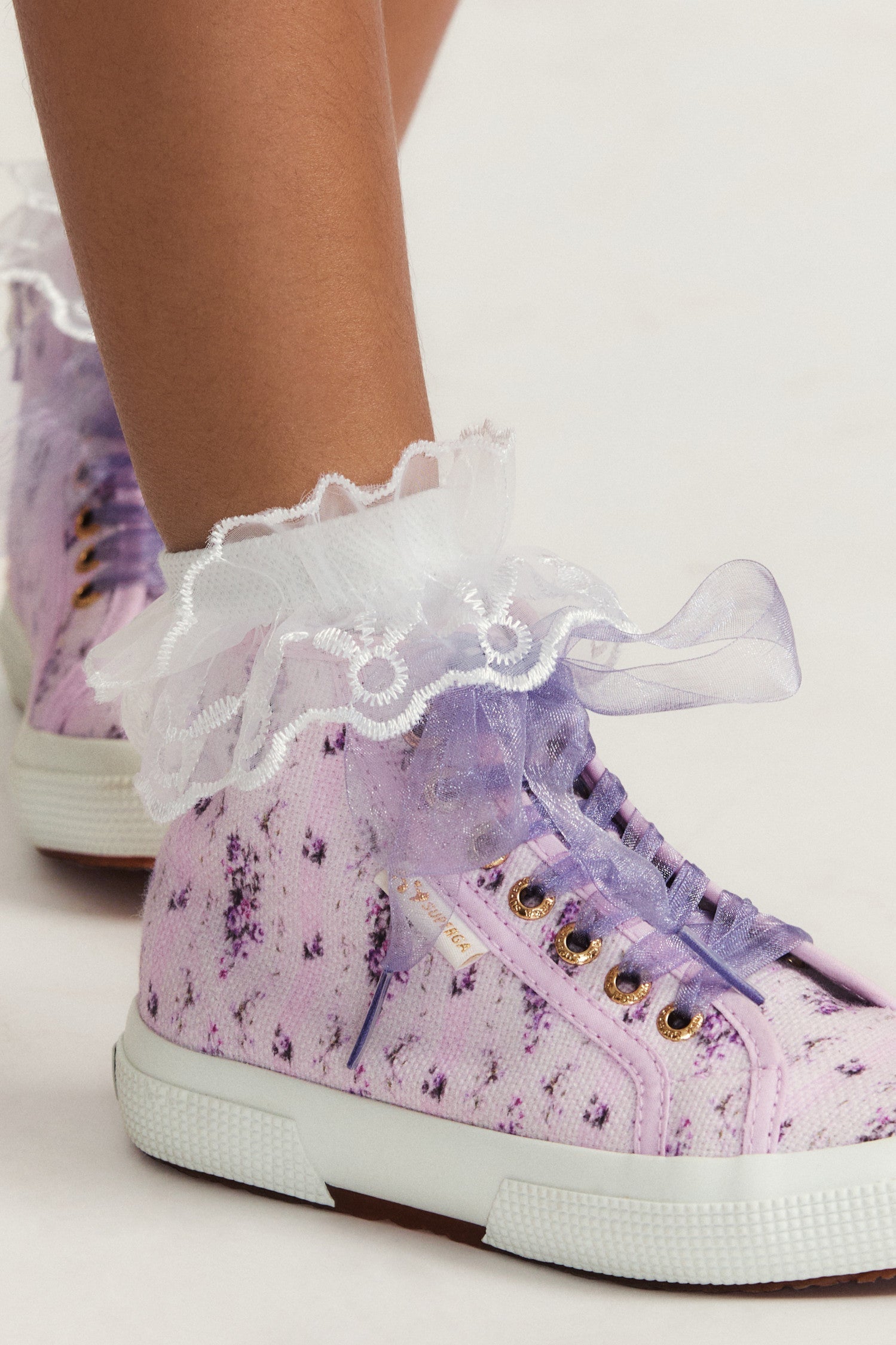 Pink and purple hightop sneakers with florals on printed cotton with tulle laces, and gold-tone eyelet details.