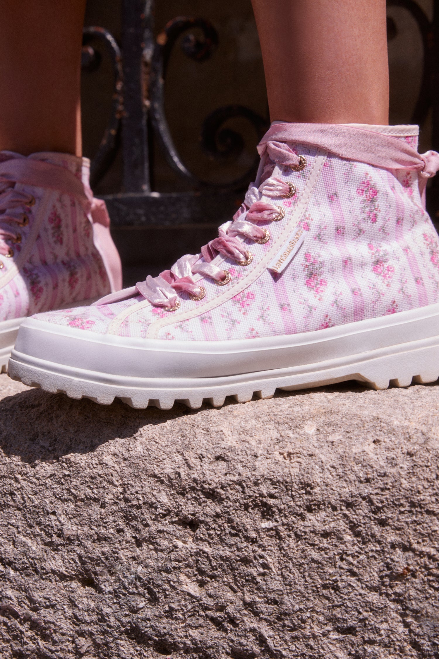 Pink hightop sneakers with florals on printed cotton with pink velvet laces, and gold-tone eyelet details.