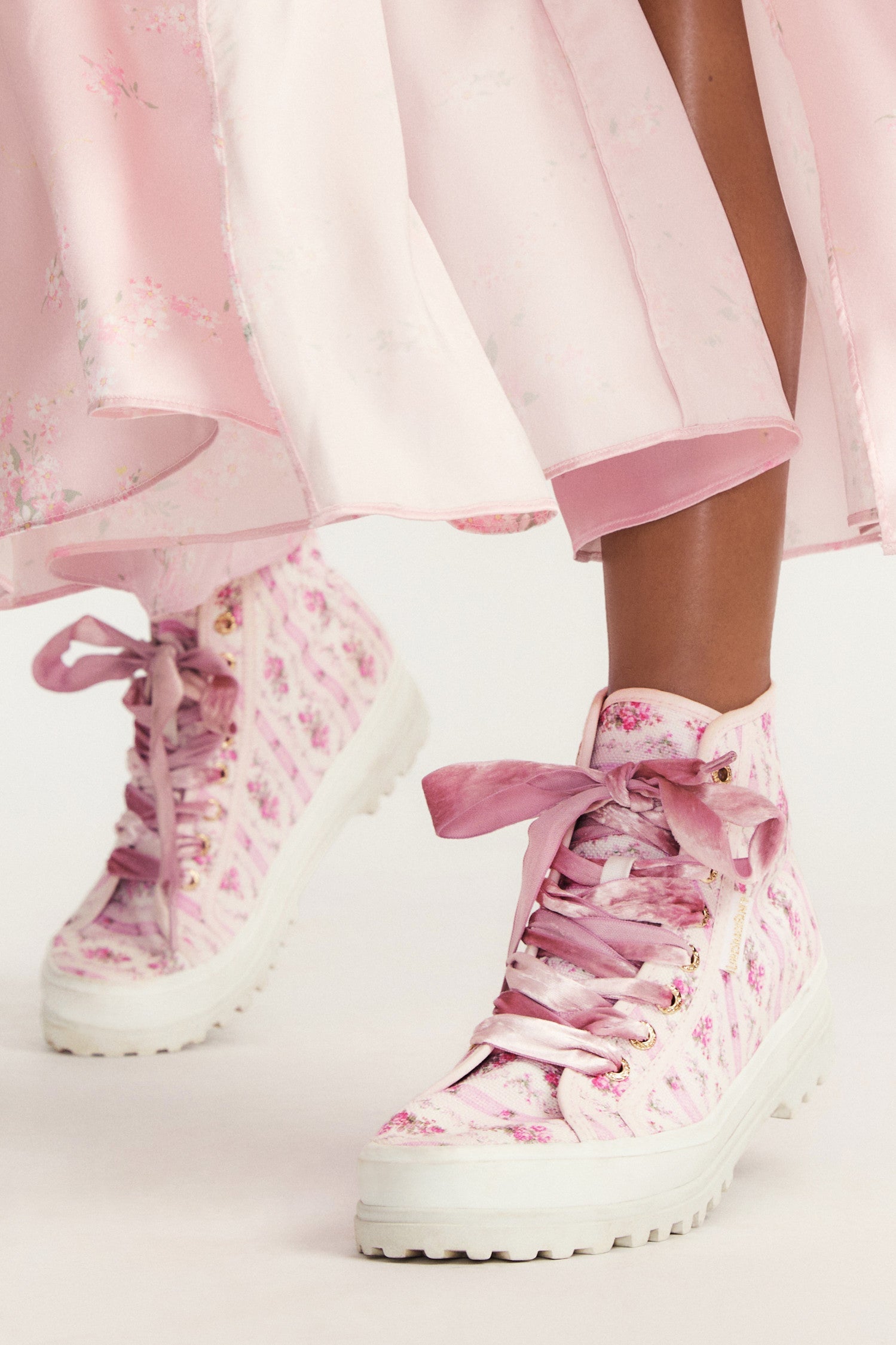 Pink hightop sneakers with florals on printed cotton with pink velvet laces, and gold-tone eyelet details.